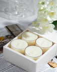 Close up lifestyle shot of a white gift box containing four Vaucluse Jasmine scented tealights, styled on a surface with fresh white jasmine blossoms.