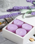 Close up lifestyle shot of a white gift box containing four purple Vaucluse Lavender soy tealights, styled on an open magazine with decorative lavender stems.