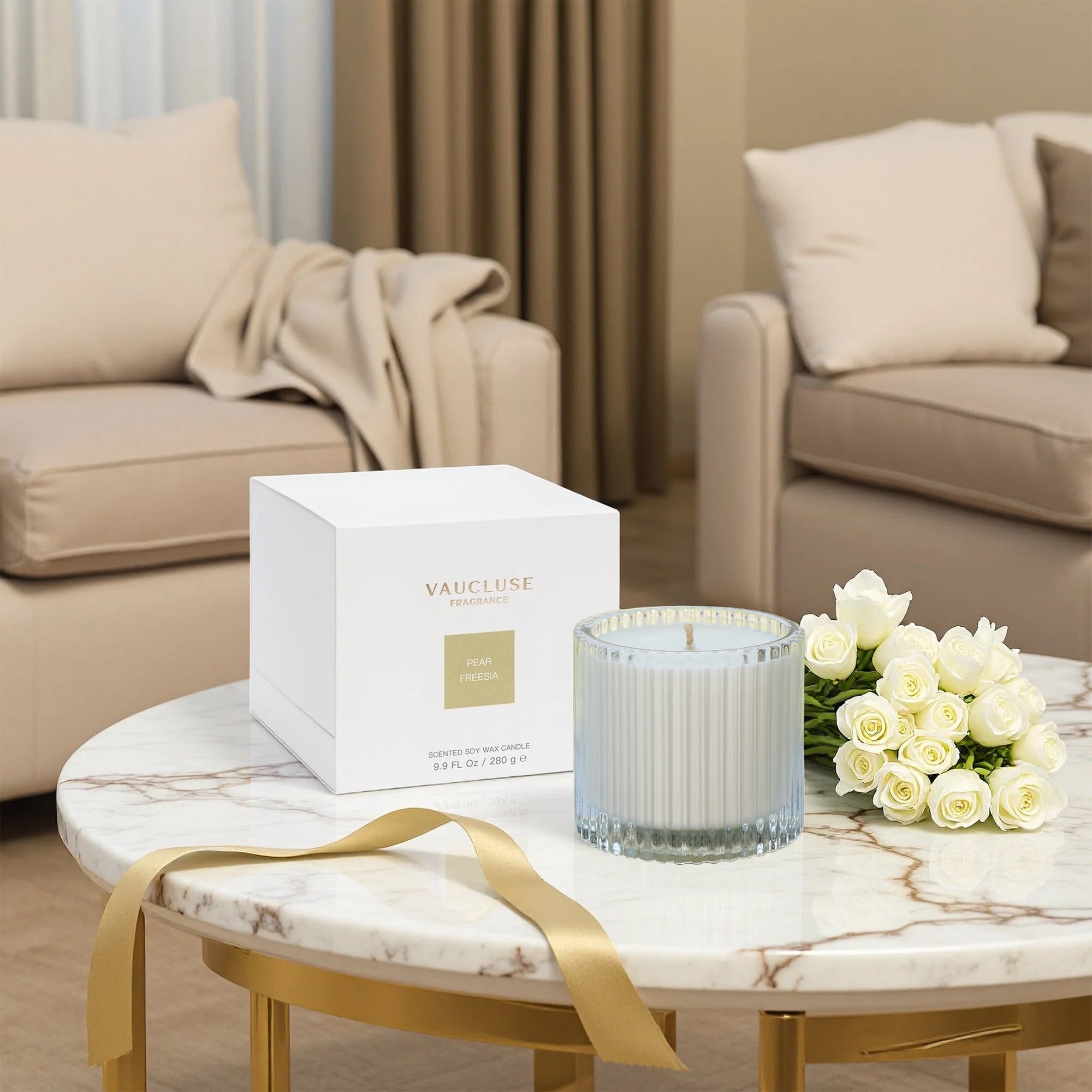 An unlit Vaucluse luxury scented candle sitting next to its elegant white and gold packaging box on a marble coffee table in a modern living room.