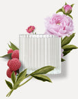 Top view of a ribbed clear glass Vaucluse candle jar beautifully arranged with fresh pink peonies and ripe red lychee fruits.