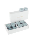 An open luxury white Vaucluse box set displaying premium grey blue velvet scented tealight candles arranged in a tiered 16-pack tray.