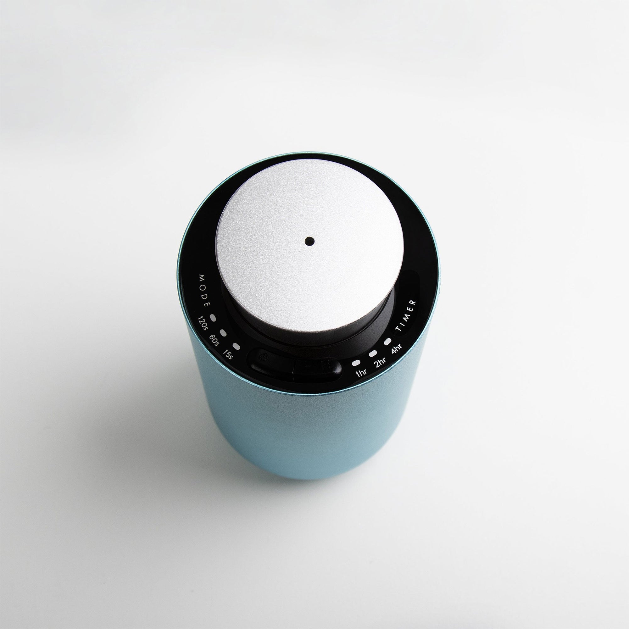 An overhead top-down view of the circular teal and silver waterless diffuser highlighting its central mist nozzle and touch-sensitive interface.