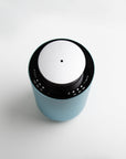 An overhead top-down view of the circular teal and silver waterless diffuser highlighting its central mist nozzle and touch-sensitive interface.