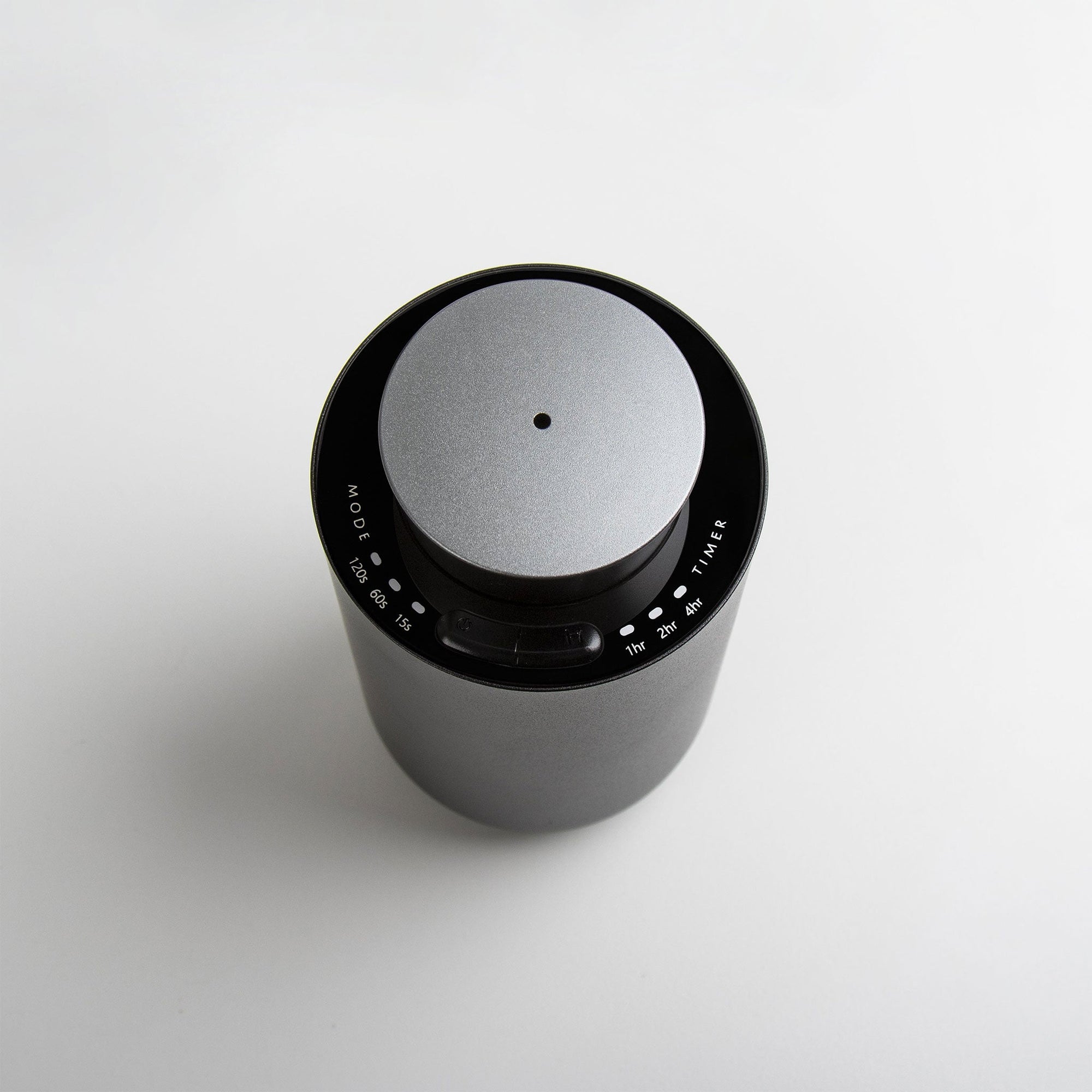 A high-angle top-down view of the circular gun metal waterless diffuser highlighting the central scent mist nozzle and clean interface.