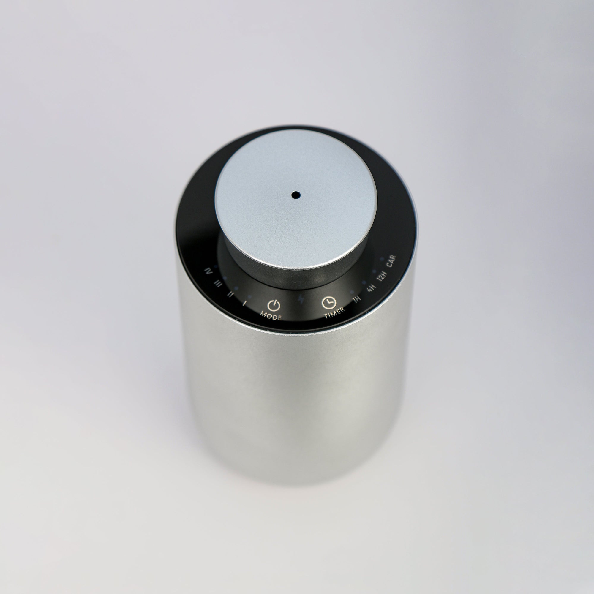 An overhead top-down perspective of the circular silver waterless diffuser, showing the central scent mist nozzle and touch control panel layout.