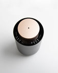 An overhead top-down view of the round black and rose gold waterless diffuser, showing the central mist port nozzle and touch setting indicators.