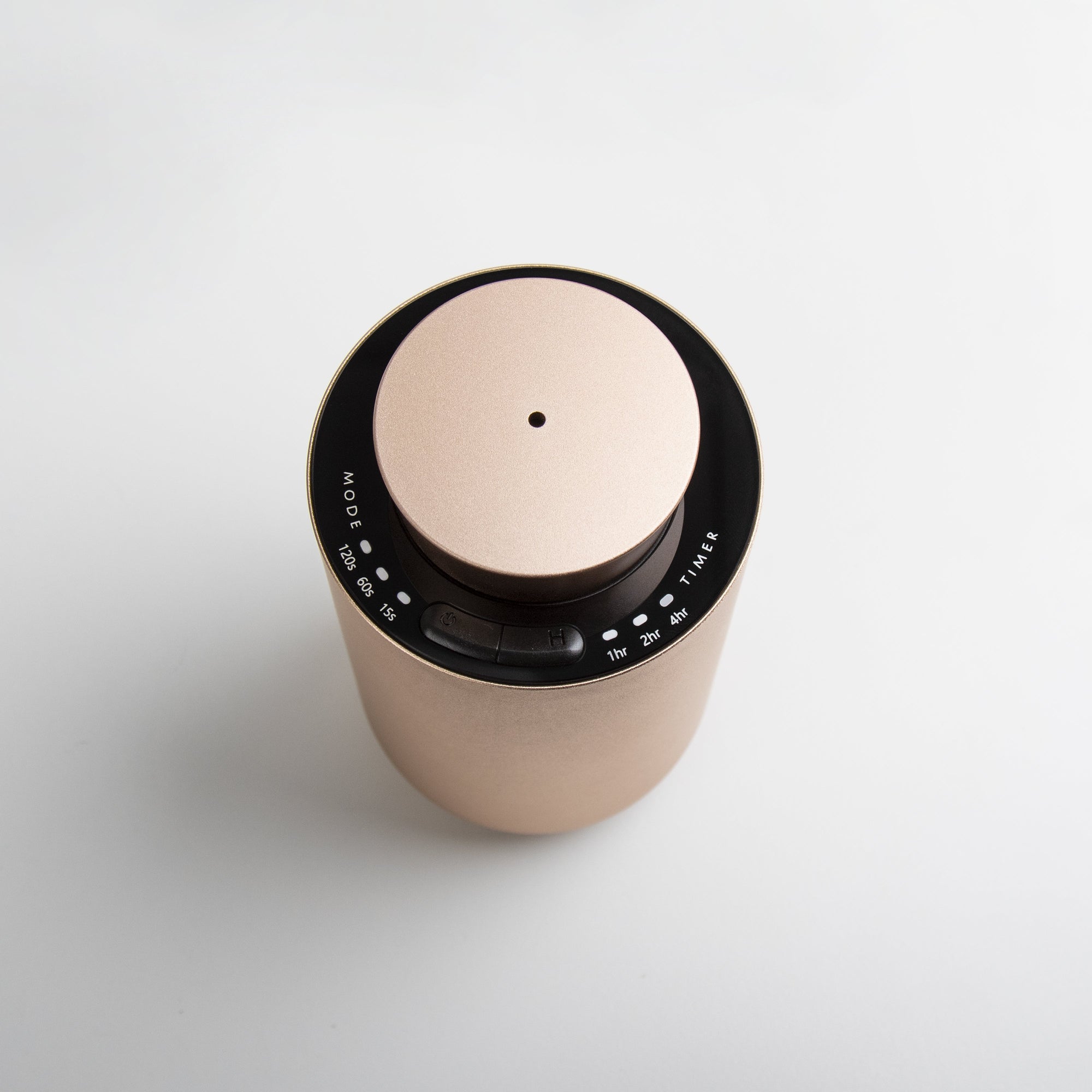 An overhead top-down perspective of the round rose gold diffuser, showing the central mist nozzle port and the black touch control panel surrounding the lid.